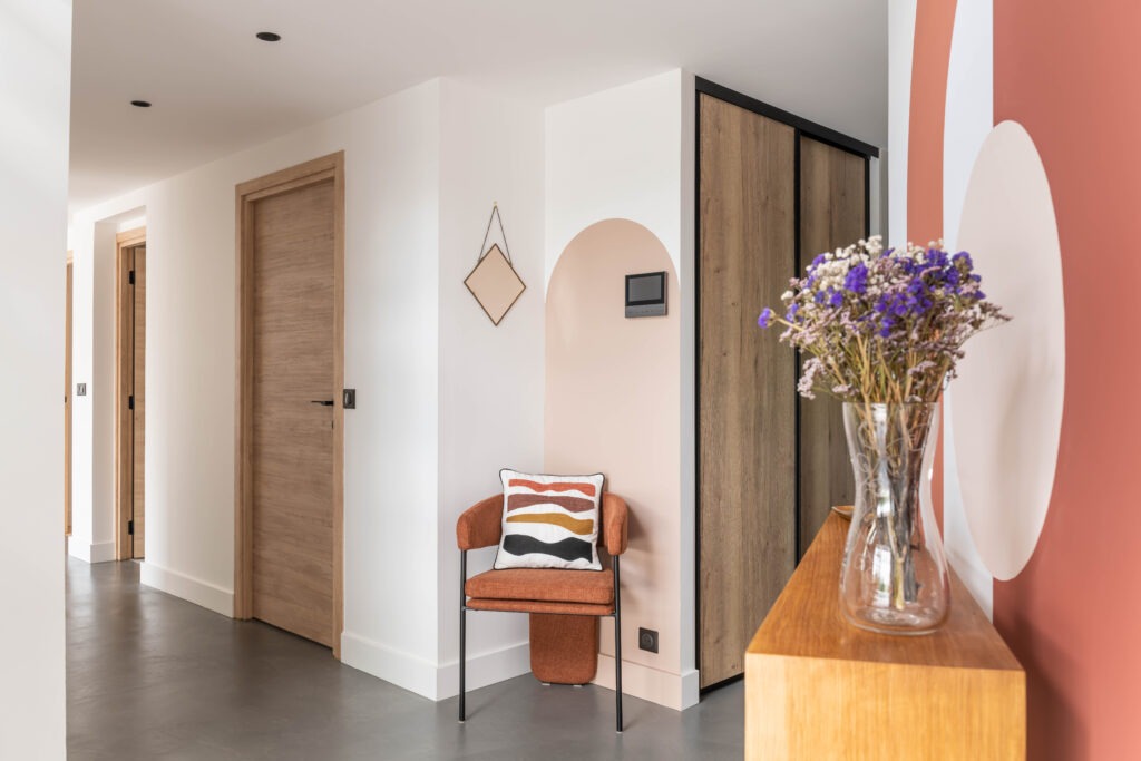 Entrée avec chaise design, arche peinte et mobilier en bois décorée par Julie Porcella, décoratrice d’intérieur à Grenoble et en Isère