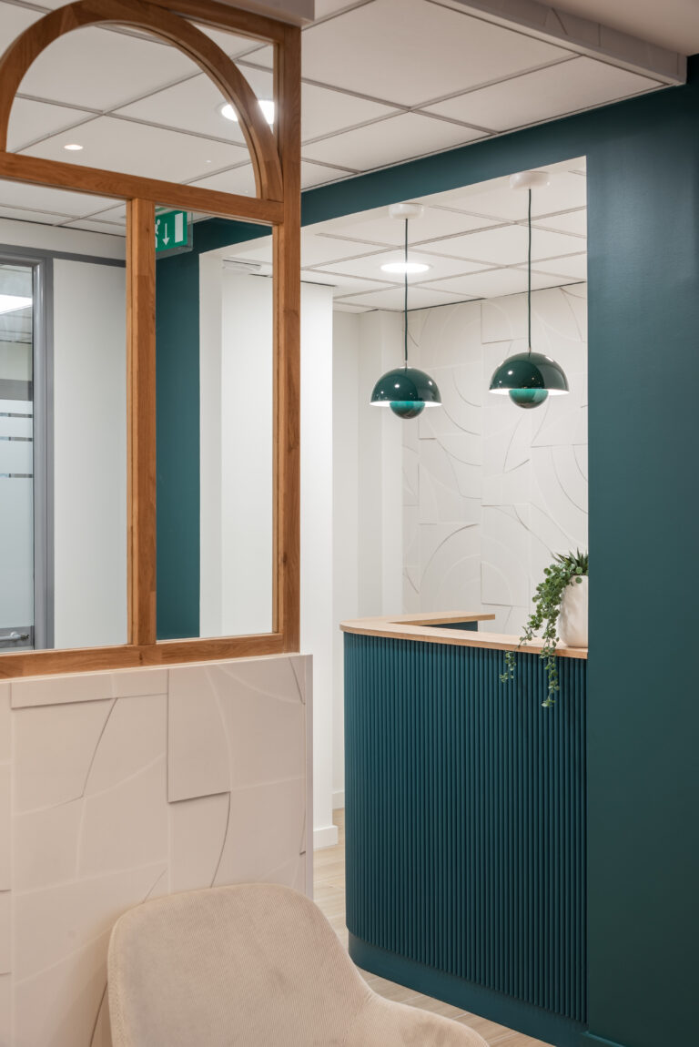 Comptoir d’accueil sur mesure avec suspensions design vert foncé et mur texturé, office notarial aménagé par Julie Porcella Aménagement d’un espace professionnel en Isère – Jolis Projets.