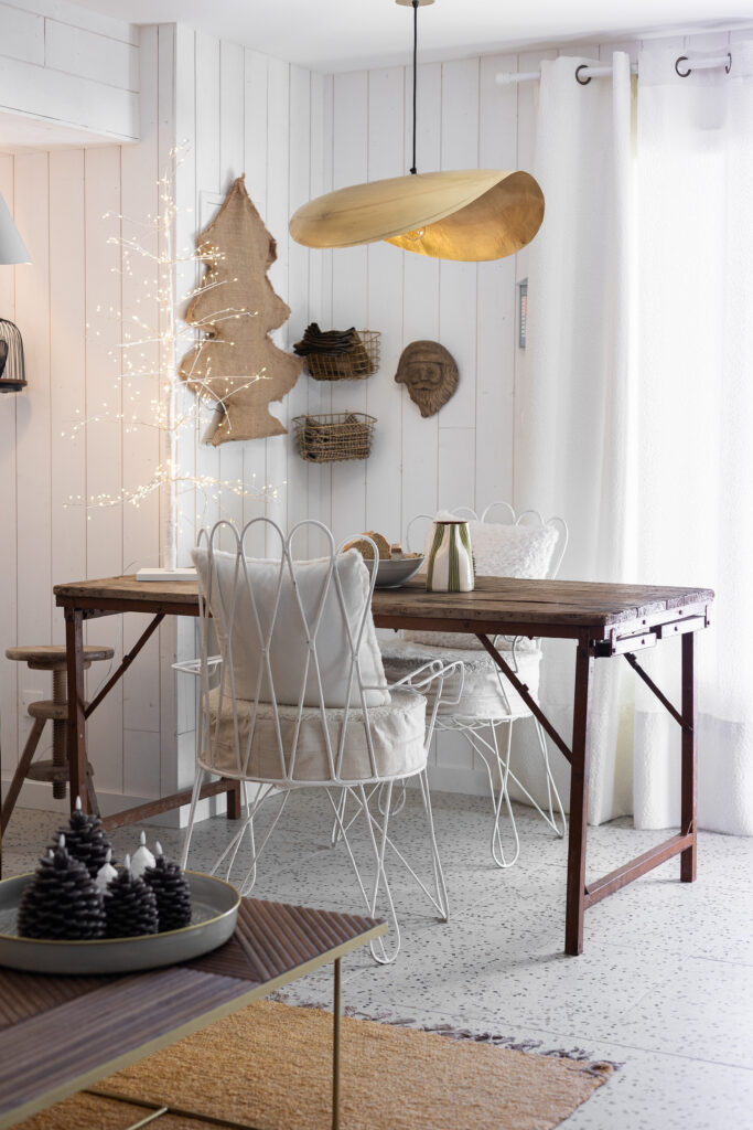 Salle à manger du projet M Vercors avec table en bois brut, chaises en métal blanc, suspension dorée et arbre lumineux décoratif. Projet de décoration intérieure Isère - residentiel.