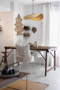 Projet M Vercors – Salle à manger chaleureuse et lumineuse Salle à manger du projet M Vercors avec table en bois brut, chaises en métal blanc, suspension dorée et arbre lumineux décoratif. Projet de décoration intérieure Isère - residentiel.