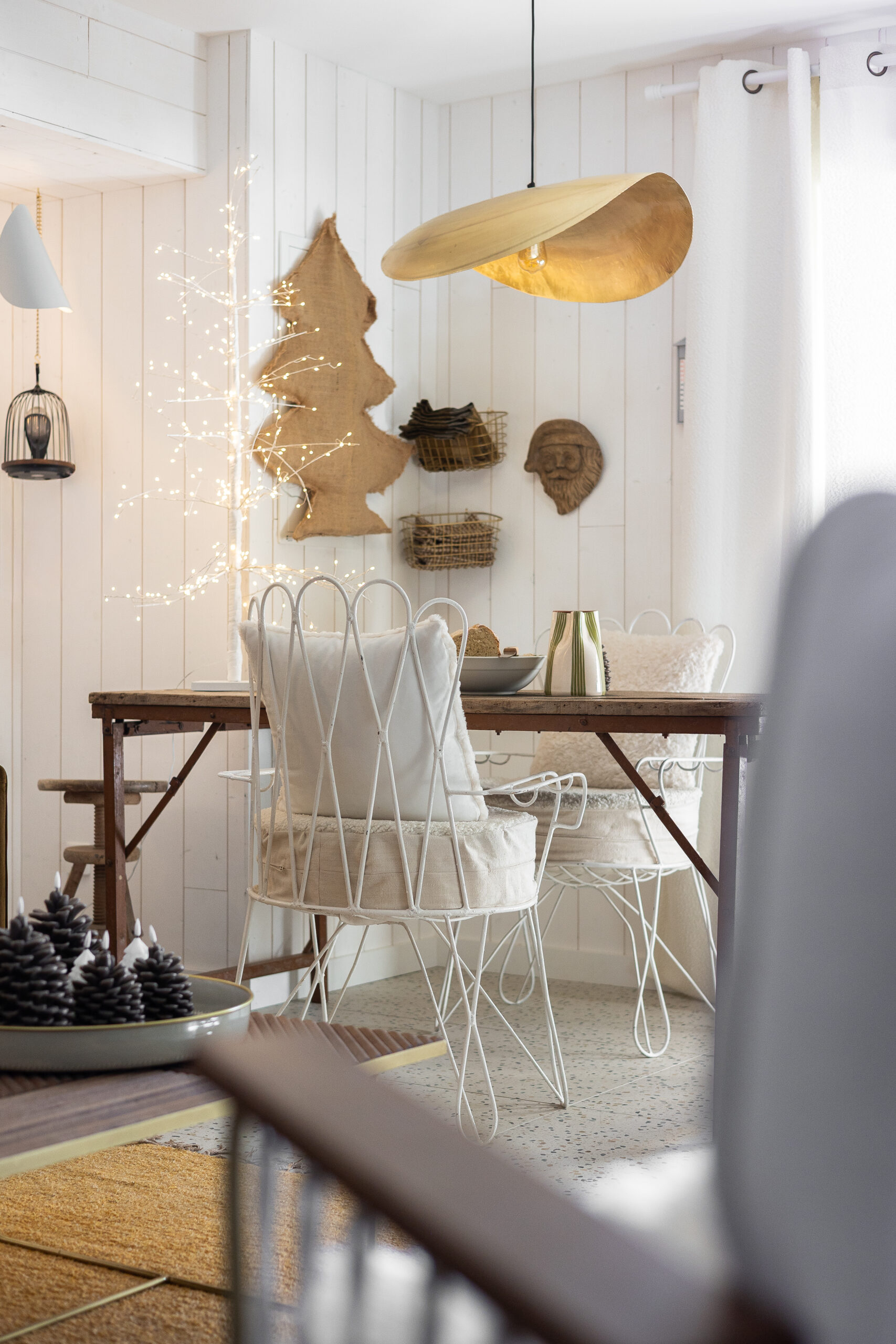 Salle à manger chaleureuse – Projet M par Julie Porcella décoratrice intérieure Grenoble Salle à manger cosy décorée par Julie Porcella, décoratrice d’intérieur à Grenoble et en Isère, avec suspension dorée, chaises blanches en métal et ambiance lumineuse – Projet M dans le Vercors.