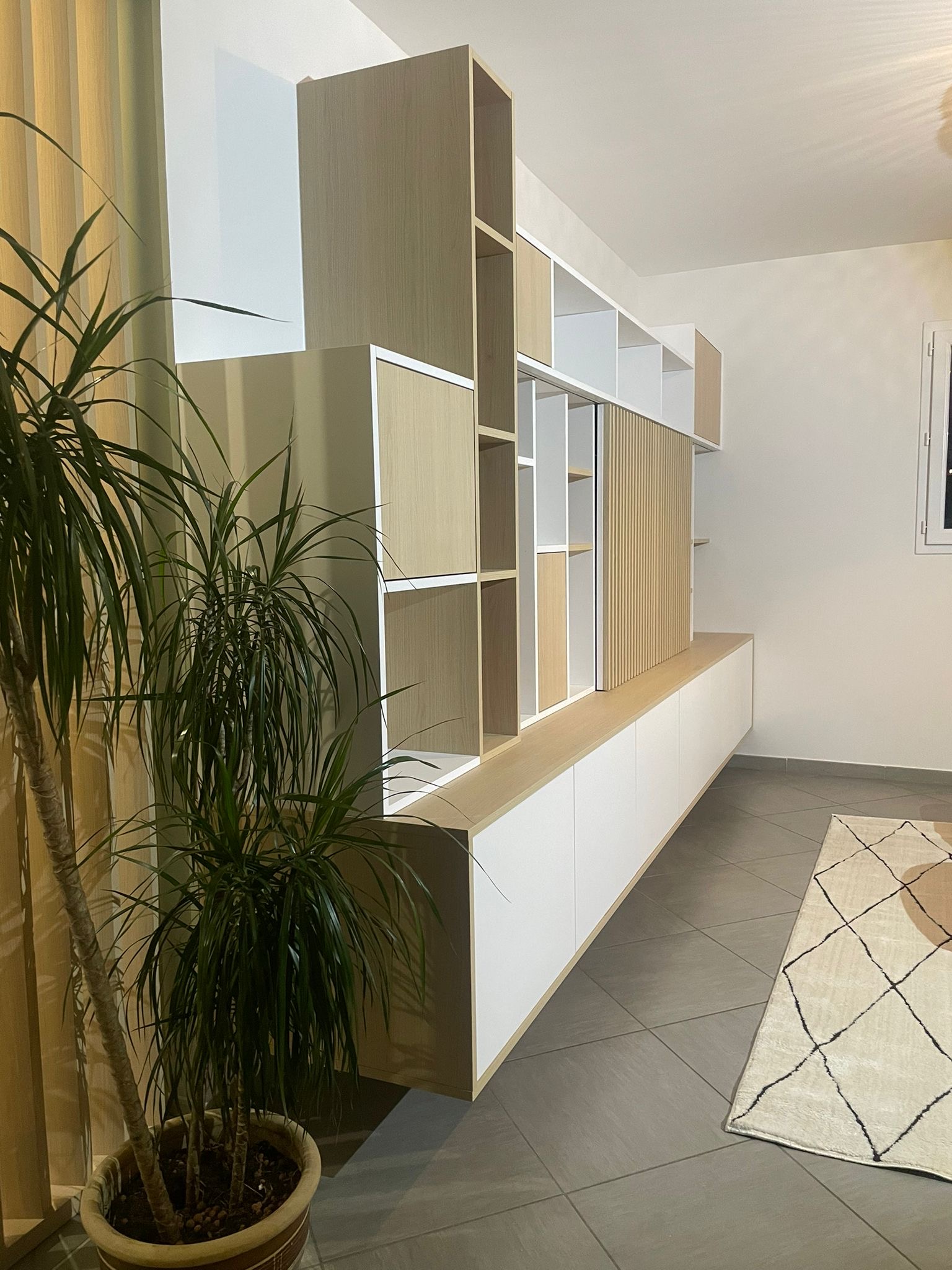 Projet S&V – Modernité et chaleur sur-mesure Meuble mural sur-mesure en bois clair et blanc, avec rangements ouverts et fermés, style moderne et chaleureux – Projet S&V.