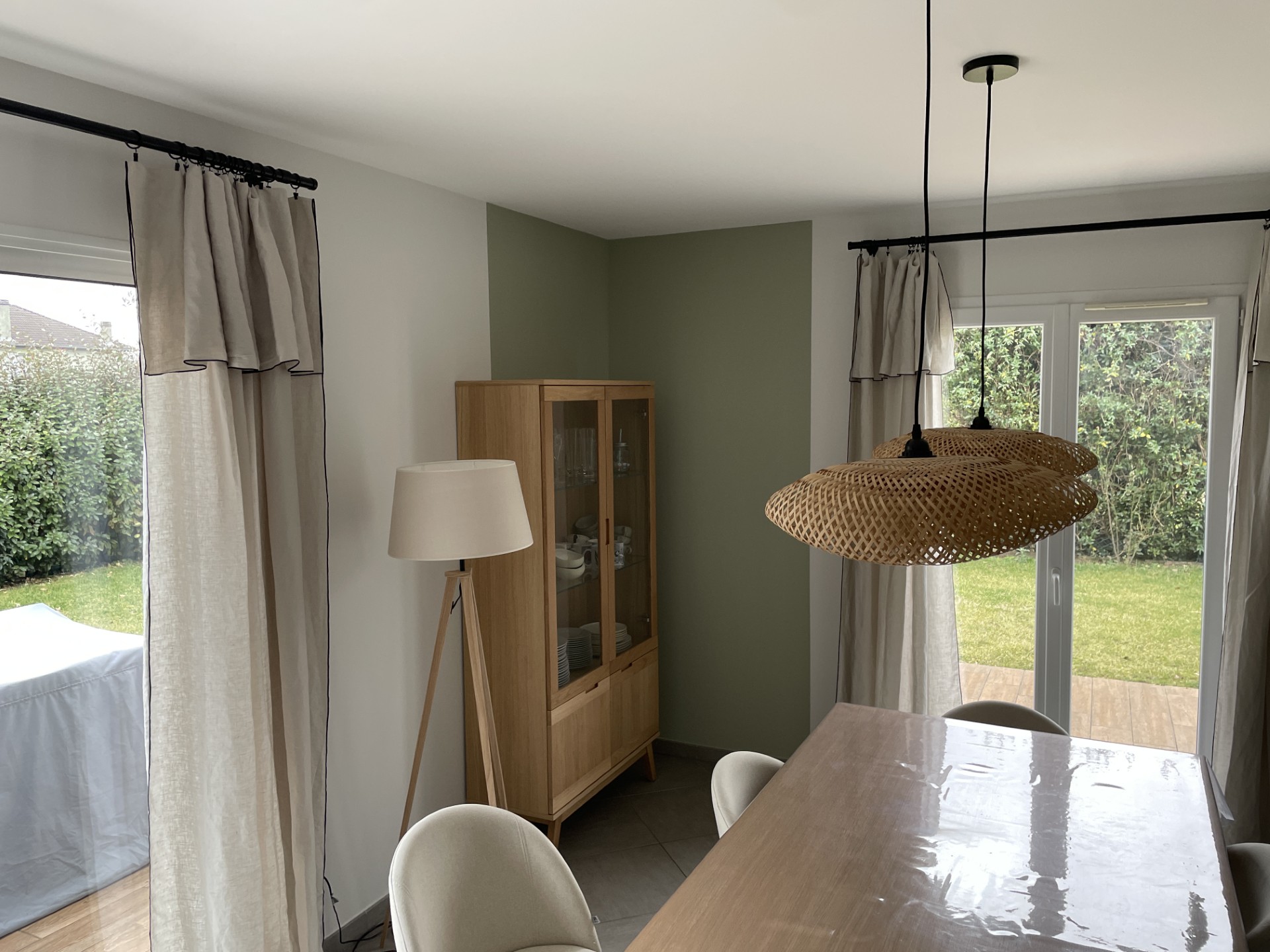 Salle à manger moderne et naturelle avec suspension en rotin et meuble vitrine en bois clair – projet décoration Grenoble par Julie Porcella, Jolis Projets.